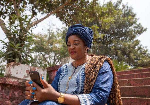 African woman dressed traditionally uses her smartphone, woman and technology concept